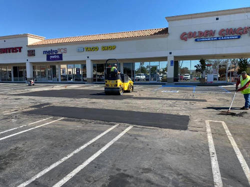 Crew repairing a pothole in a parking lot.